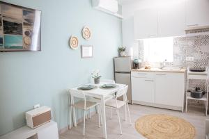 a white kitchen with a white table and chairs at Meraki Seaside Apartment in Stavros +15 photos