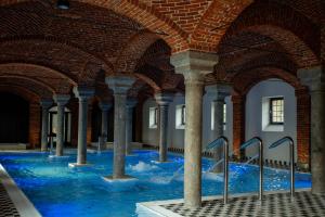 an indoor pool with blue water in a building with columns at Ostoja Chobienice in Chobienice