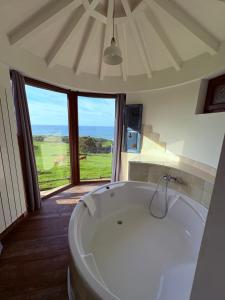 una gran bañera blanca en una habitación con ventana en Posada Punta Liñera, en San Vicente de la Barquera