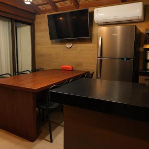 a kitchen with a stainless steel refrigerator and a table at La Playa Bangalô in Arraial d'Ajuda
