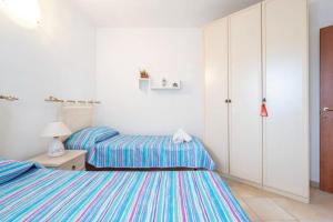 a bedroom with two beds and a white cabinet at Delightful three room flat with patio near Budoni in Tanaunella