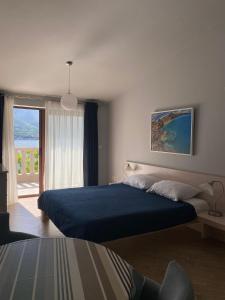 a bedroom with a bed with a blue blanket and a window at Apartments Bella di Mare in Kotor