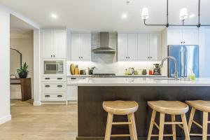 a kitchen with white cabinets and bar stools at Creekside Elegance at Timberstone in Canmore
