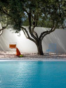 a swimming pool with two chairs and a tree at Infinity White Complex in Porto Rafti