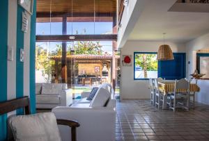 a living room with white couches and a table and chairs at Casarão de vidro - Pé na Areia - Praia Enseada dos Corais in Cabo de Santo Agostinho