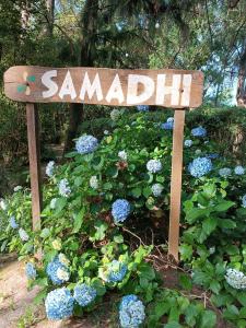a sign in a garden with blue flowers at Samadhi in Tigre