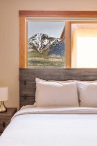 a bedroom with a bed and a window with a snow covered mountain at Mountainside - Stunning Views Downtown Location in Canmore