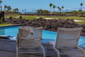 two white chairs sitting next to a swimming pool at 5BD Mauna Lani Lux Golf Estate (4) at One Ocean in Waikoloa
