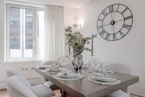 a dining room table with chairs and a large clock on the wall at Harrods Platinum Pad in London