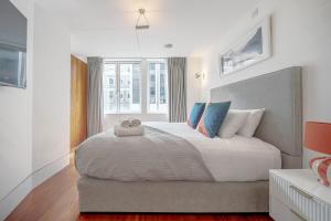 a bedroom with a large white bed with blue pillows at Harrods Platinum Pad in London
