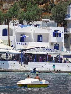 two people in a small boat in the water with a large boat at Faros Rooms in Loutro