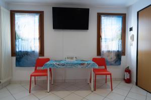 a table with two red chairs and a television on a wall at Il Faro in Chioggia