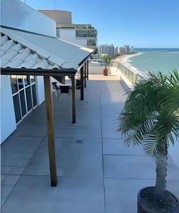 a balcony with a table and a palm tree on a building at G1104 FRENTE MAR com varanda Piscina Ar cond Garagem in Vila Velha