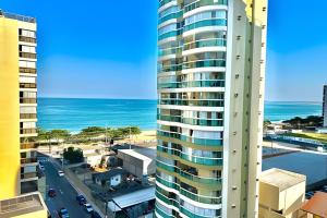 a tall building with the ocean in the background at M901 Vista Mar Ar Cond Garagem in Vila Velha