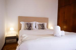 een slaapkamer met een bed met witte lakens en kussens bij De Casa Villa by GALMI in Estreito da Calheta +23 foto's