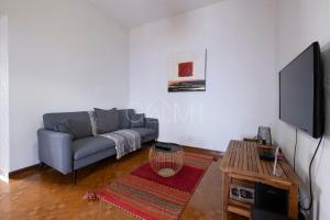 een woonkamer met een bank en een flatscreen-tv bij De Casa Villa by GALMI in Estreito da Calheta