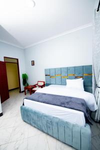 a bedroom with a large bed with a blue headboard at Private Nest Apartment 2 in Arusha