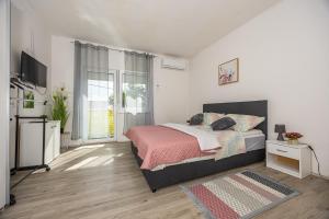 a white bedroom with a bed and a television at Dvokrevetna soba Lela in Crikvenica