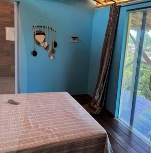 une chambre avec un lit aux murs bleus et une fenêtre dans l'établissement Hospedaria Coisa Linda Caraiva, à Porto Seguro