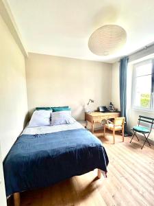 SantecにあるAgréable maison, au Dossen, à 2 pas de la plageのベッドと机と窓のある寝室
