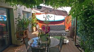 a patio with a table and a couch and an umbrella at L'Art'Home à Carnon Plage in Mauguio