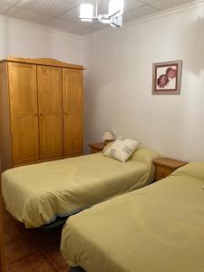 a bedroom with two beds and a cabinet at Casa Fuenteblanca in Liétor