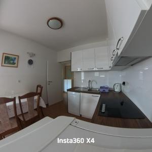 a kitchen with white cabinets and a kitchen table at Baja 2 in Lopar