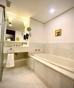 a bathroom with a tub and a sink and a mirror at Itaim Alto Padrão 2suítes MobInn 803 in Sao Paulo