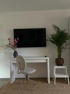 a white desk with a chair and a television on a wall at Mams-Cottage-Brunhilde in Harnischdorf