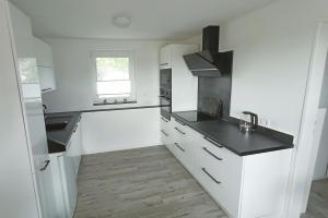 a kitchen with white cabinets and a black counter top at Fenland Mill Ranch in Wolthausen