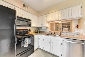 a kitchen with white cabinets and a black refrigerator at WFH-Friendly Condo Near Galleria in North Dallas! in Dallas