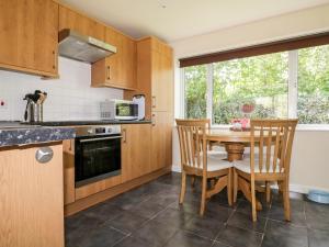 a kitchen with wooden cabinets and a table and chairs at 49 Atlantic Reach in Newquay