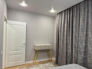 1 dormitorio con cama, mesa y cortina en Жана Сарыарка, en Karagandá 2 fotos más