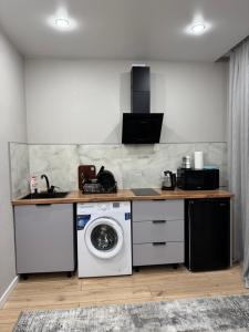 una cocina con lavadora bajo una barra en Жана Сарыарка, en Karagandá