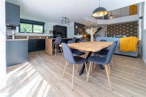 a kitchen and dining room with a wooden table and blue chairs at Les Combettes - Terrasse, Jardin & Proche Lac in Moyrazès