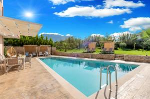 a swimming pool with a patio and a table and chairs at Allas Villa Heated Pool in Chania Town
