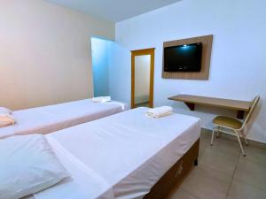 una stanza con due letti, una scrivania e una televisione di Manacá Hotel a Foz do Iguaçu