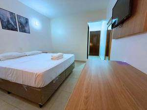 una camera da letto con un letto e una televisione a parete di Manacá Hotel a Foz do Iguaçu