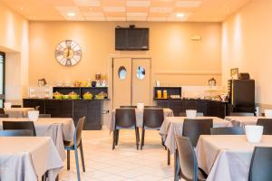 a dining room with tables and chairs and a kitchen at Al Centro in Verbania