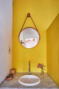 lavabo con espejo en una pared amarilla en Pousada Ziriguidüm, en Caraíva