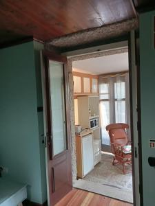 Una habitación con una puerta abierta a una cocina con una silla. en Quinta dos Campos - Apartamento 2, en Braga