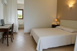una camera da letto con un letto e una scrivania con un computer di Agriturismo Nuraghe Tuttusoni a Aglientu
