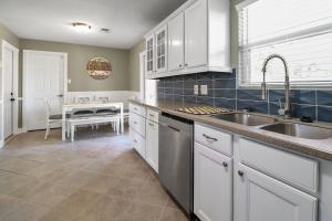 a kitchen with white cabinets and a sink and a table at Hot Tub Relax. Vacation Mode Activated in Galveston +8 photos