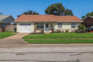 a house with a garage and a grass yard at Hot Tub Relax. Vacation Mode Activated in Galveston