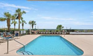 a swimming pool with palm trees and the ocean in the background at Ashworh 1001 Four Bedroom Condo Oceanfront "Picture Perfect" in North Myrtle Beach
