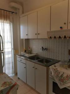 una cucina con mobili bianchi e un lavandino di Markou Mpotsari 19 & Hras, Perigiali , Korinthias a Kórinthos