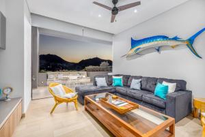 a living room with a gray couch and a blue fish on the wall at Cabo Marina Luxury Condo Jacuzzi & Terrace in Cabo San Lucas