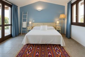 una camera con un letto bianco e una parete blu di Agriturismo Nuraghe Tuttusoni a Aglientu