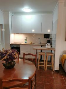 a kitchen with white cabinets and a table and chairs at Casa da Praia do Vau in Portimão