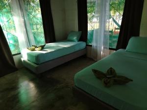 a room with two beds and windows with bows at Happy Monkeys in Puerto Jiménez